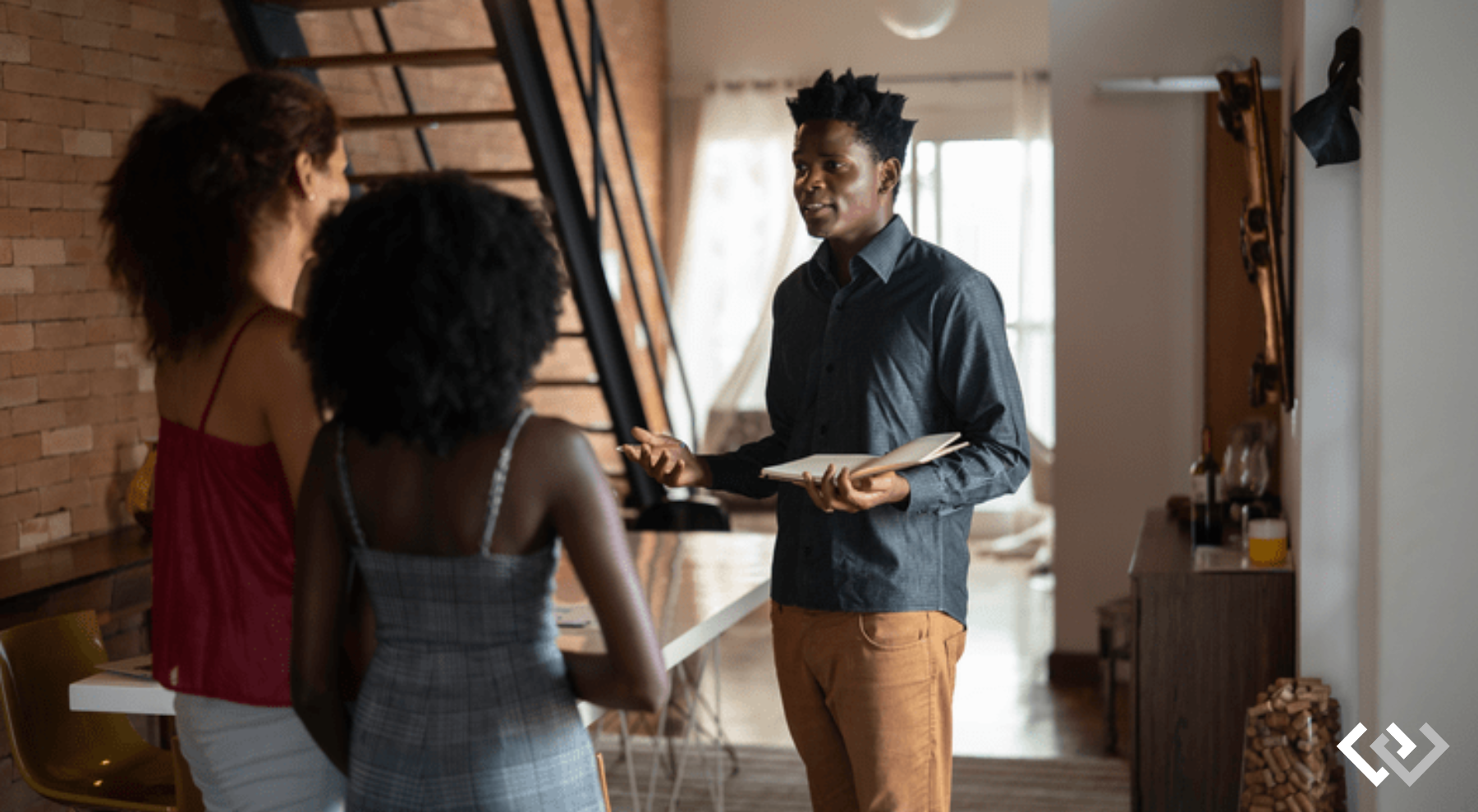 man holding a clipboard, speaking to two women.