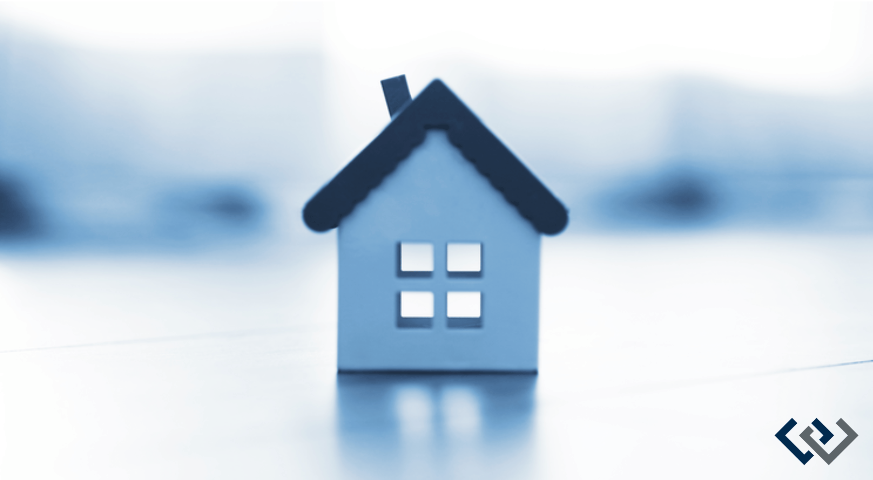 A little blue model of a house sits on a blurred background