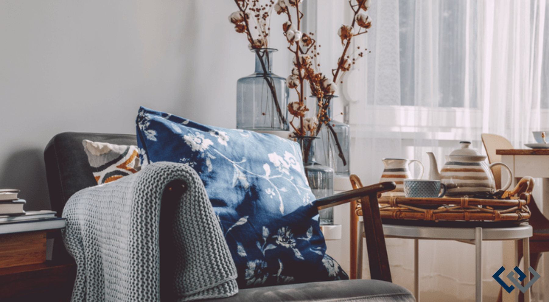 chair with a pillow, a table set with books, a plant in the background