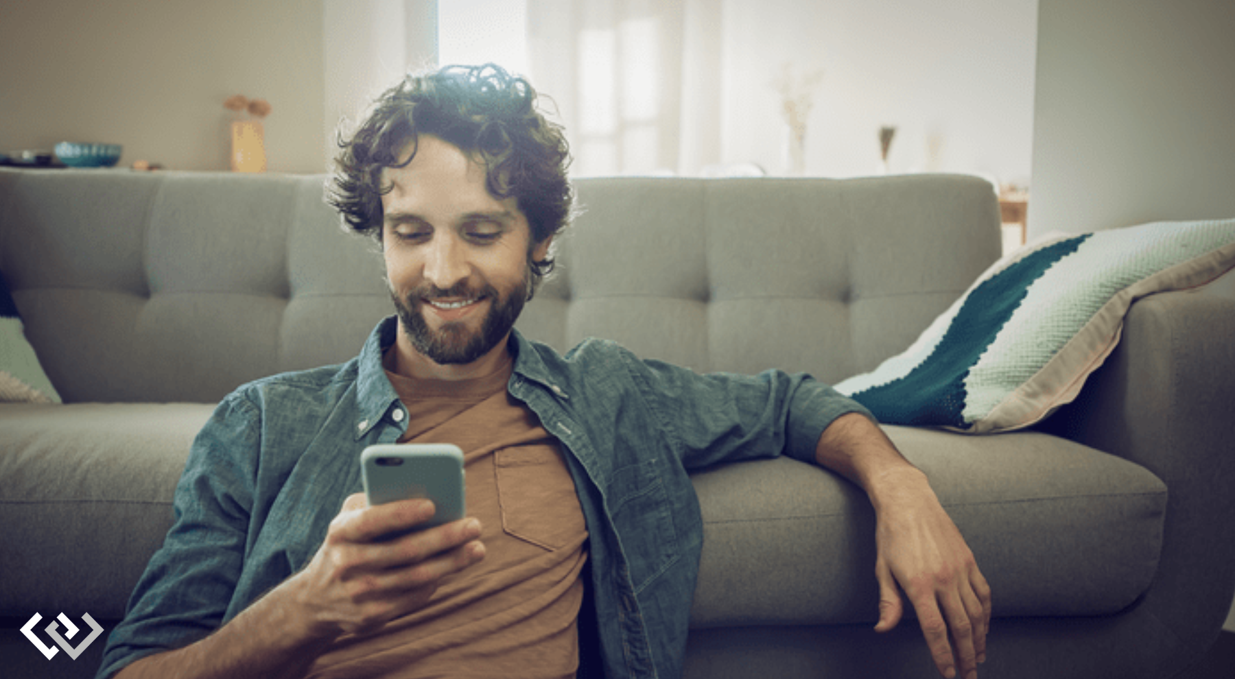 man holding his phone, sitting on the floor in front of a couch