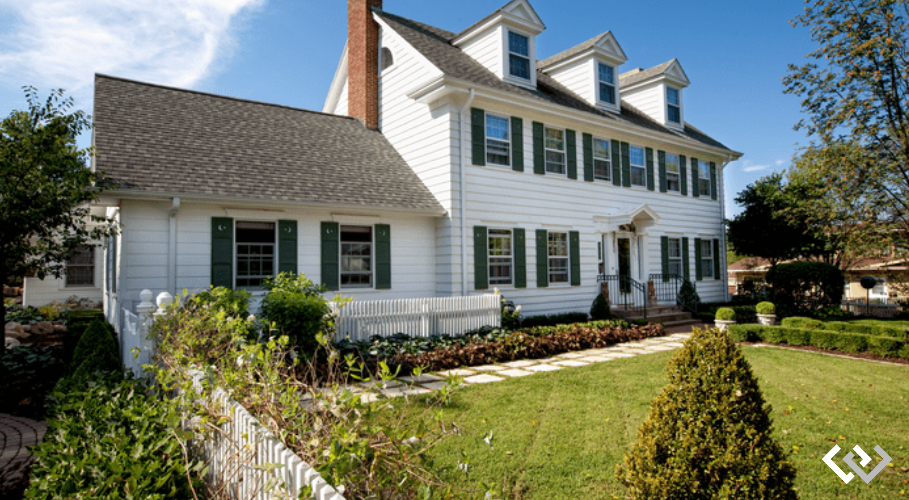 The facade of a larger white house with landscape yard