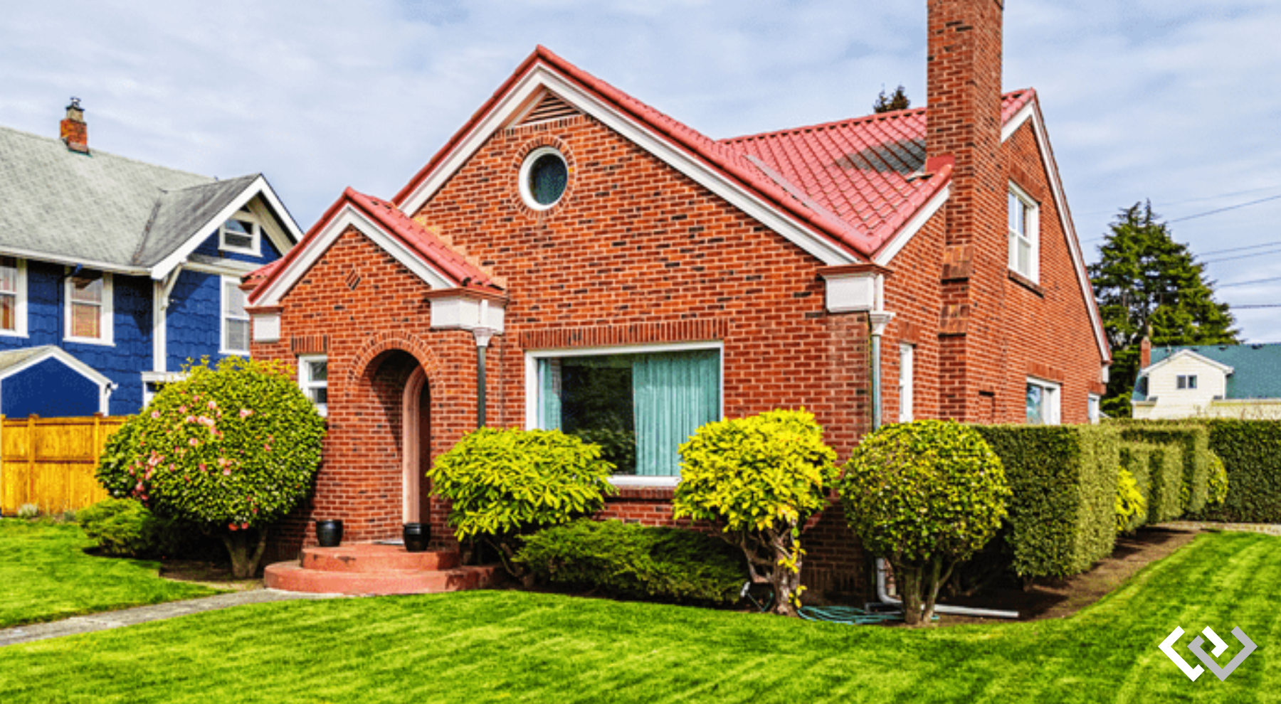 bright red brick home featured on a green lawn, situated among other homes